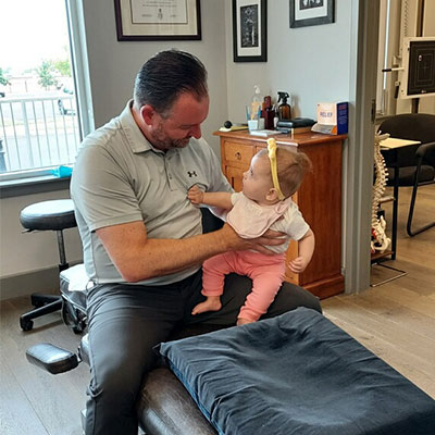 Dr Matt Savona holding and examining a smiling infant in Dublin PA