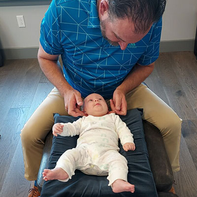 Dr Matt Savona adjusting a smiling infant in Dublin PA